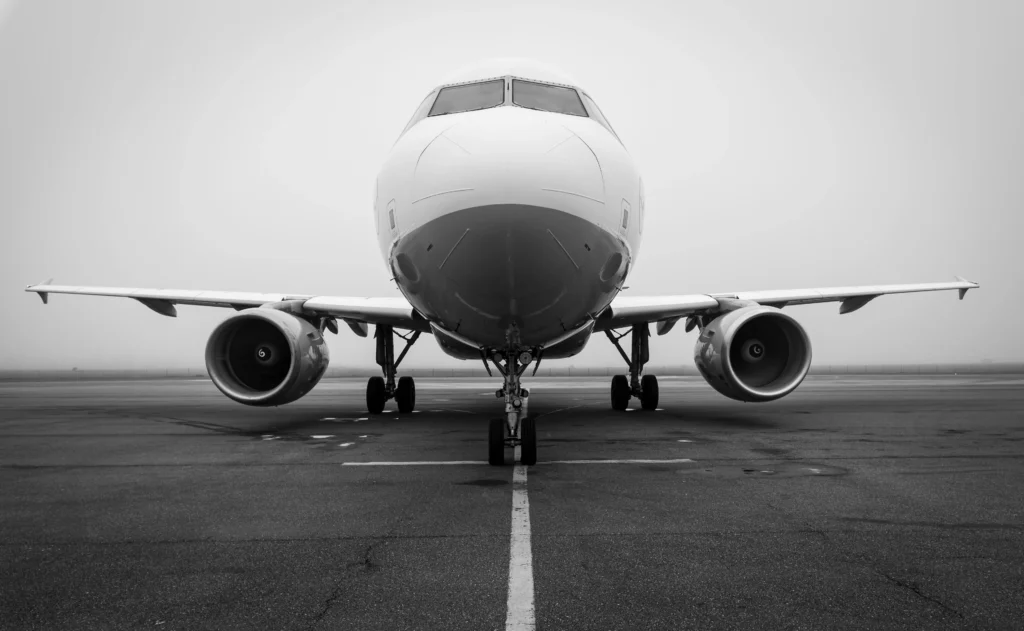 Front view of a large commercial jet on a runway, with engines on each side, in black and white.