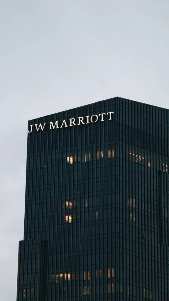 JW Marriott hotel building with a dark glass façade and lit windows against a pale sky.