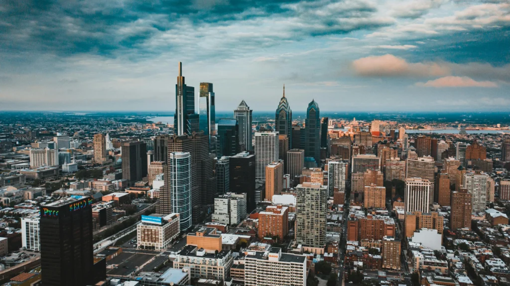 Aerial view of a dense downtown skyline with tall glass skyscrapers and a blue sky.