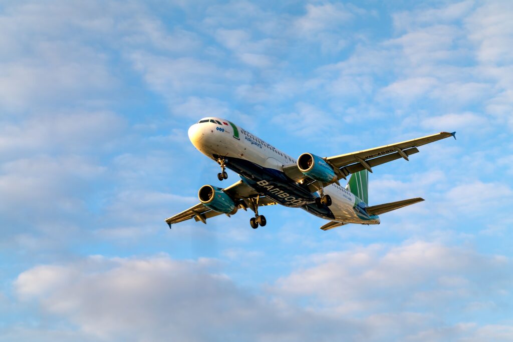 Commercial passenger jet climbing into a blue, cloud-streaked sky with landing gear down