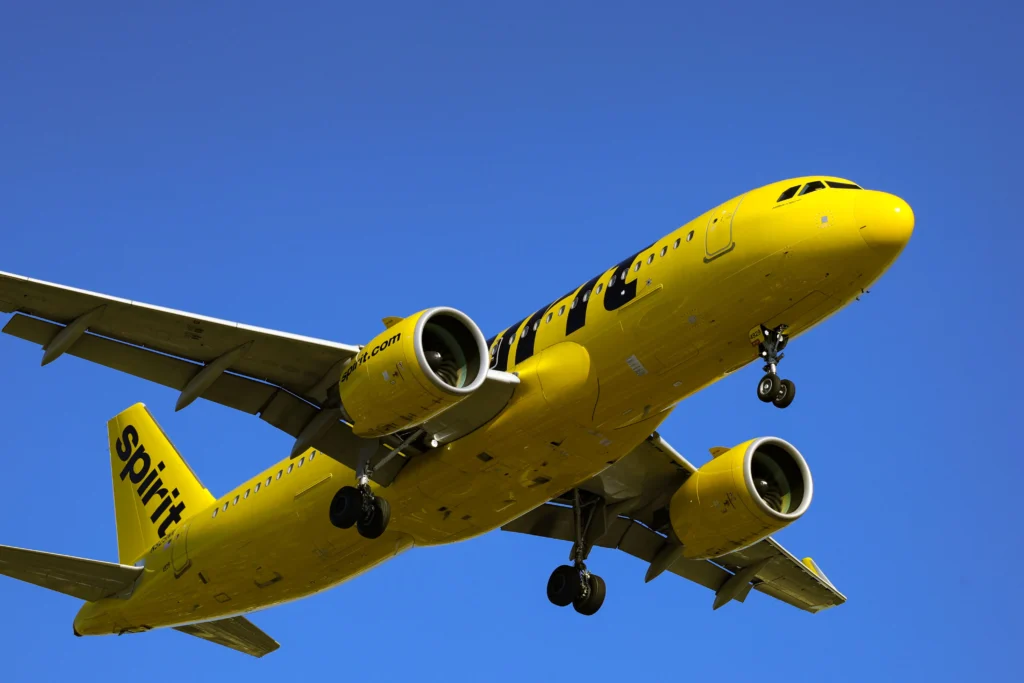 Yellow Spirit Airlines aircraft in flight against a clear blue sky, showing nose and engines clearly visible.