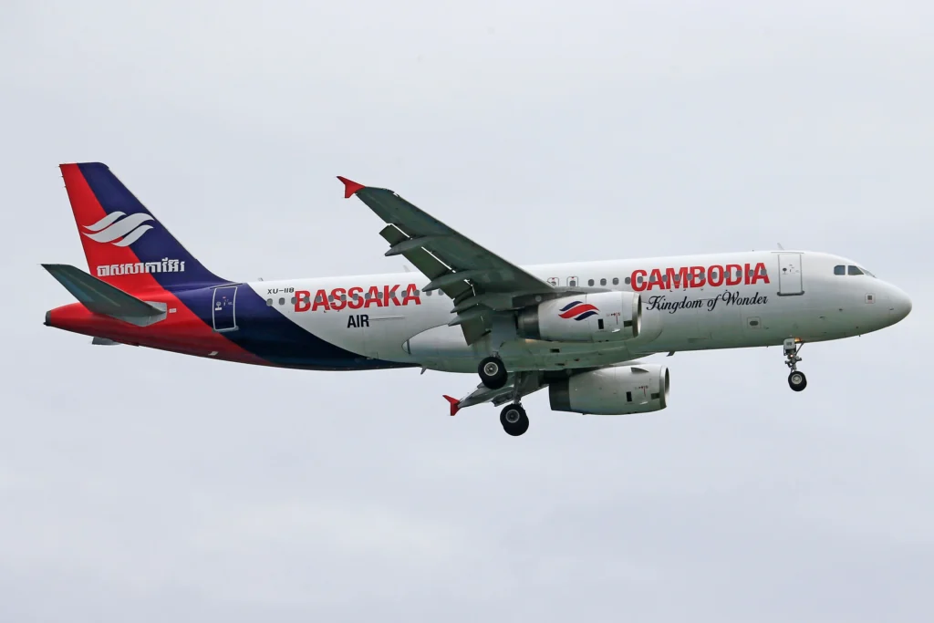 Passenger jet in flight with Cambodia Bassaka Air livery, red/blue tail and 'Cambodia Kingdom of Wonder' on the fuselage.