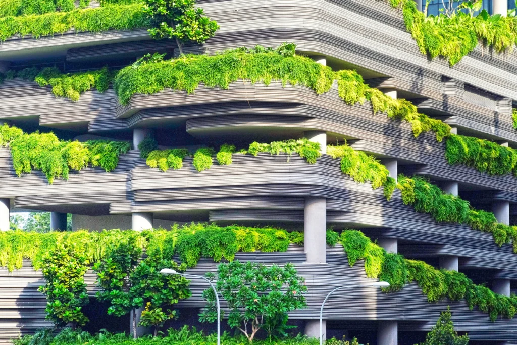 Greenery-covered, tiered concrete building with horizontal fins and hanging plants on each level.